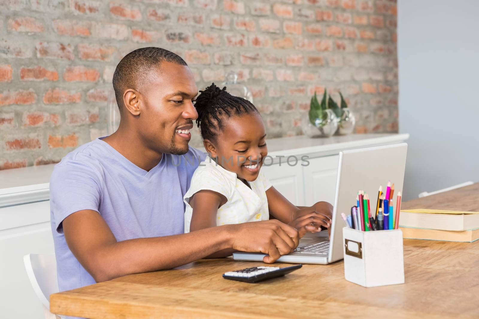 Cute daughter using laptop at desk with father by Wavebreakmedia