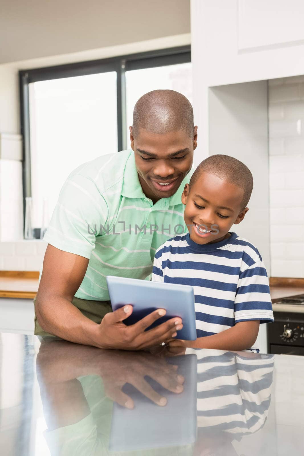 Father using tablet with his son in the kitchen