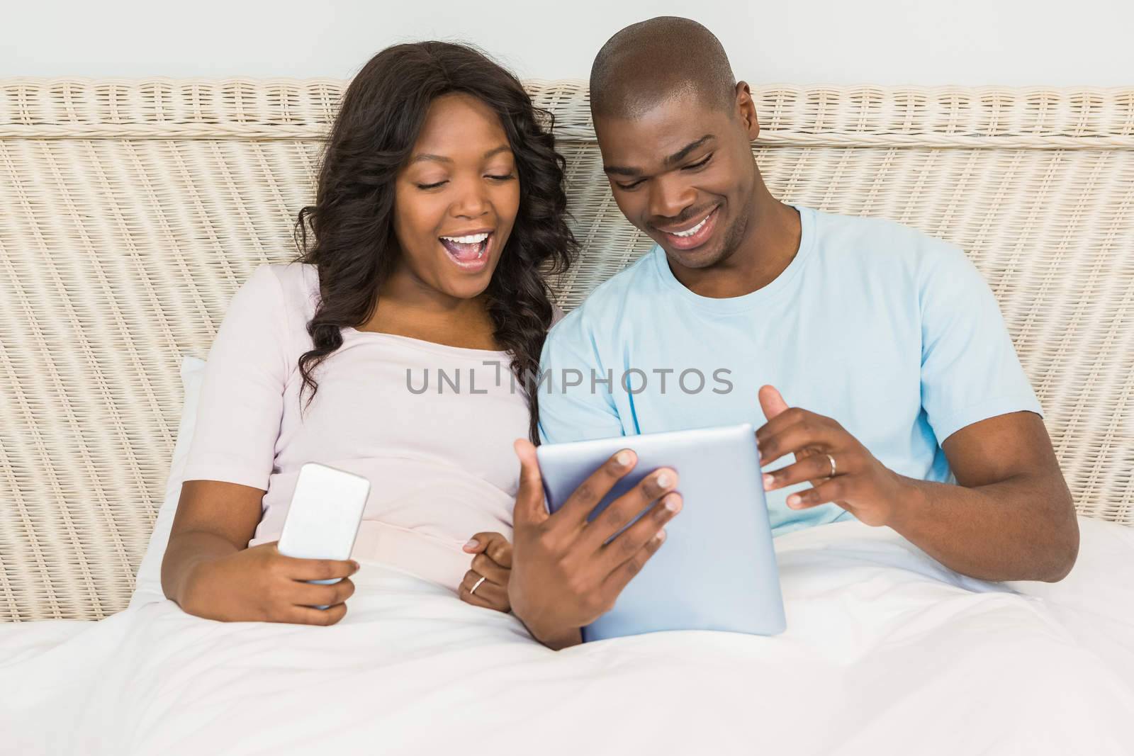 Relaxed couple using technology on bed at home 