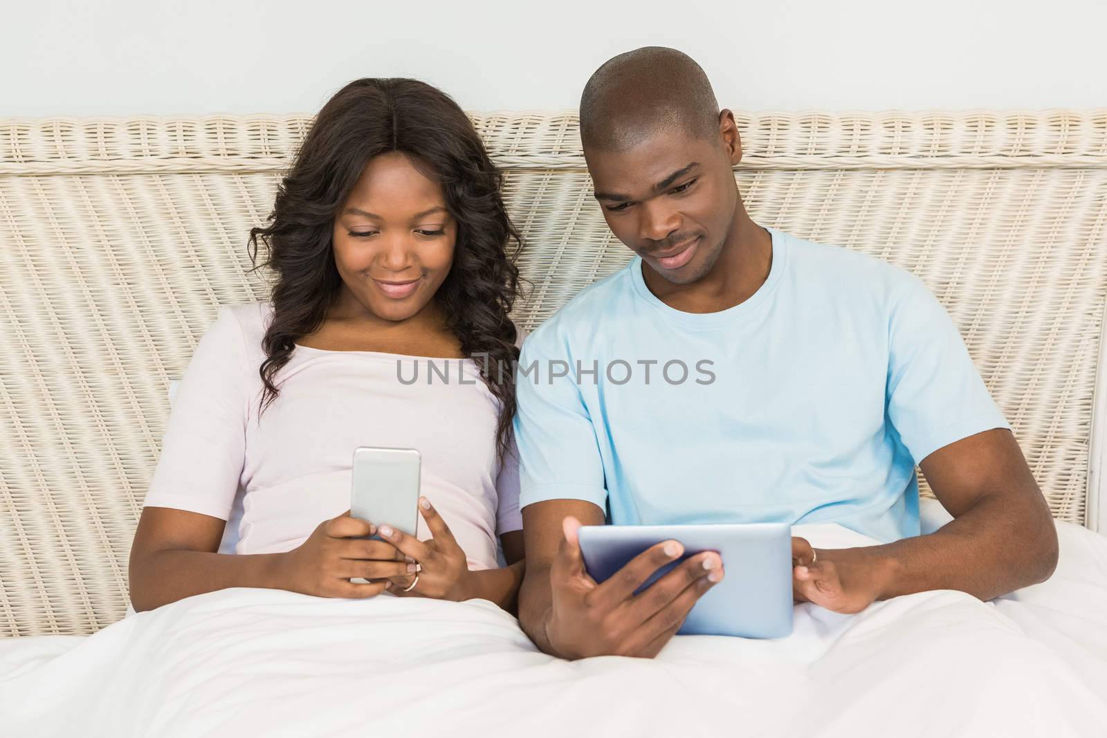 Relaxed couple using technology on bed at home 