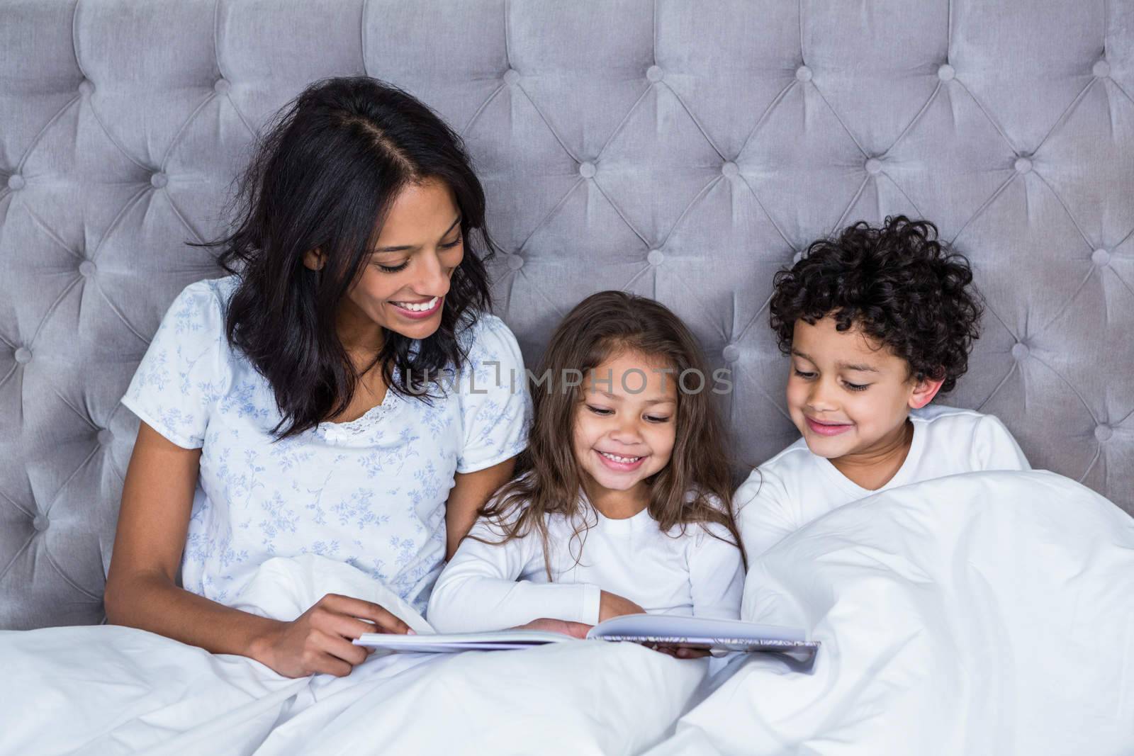 Happy family reading book on the bed by Wavebreakmedia
