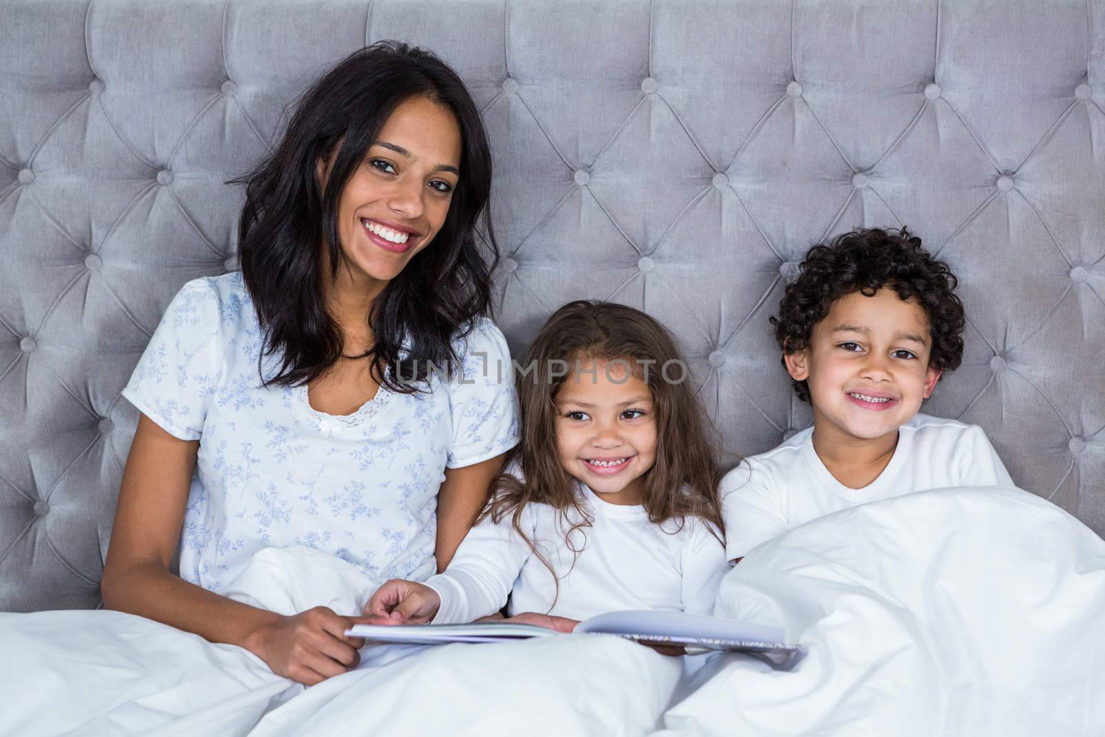Portrait of happy family reading book on the bed