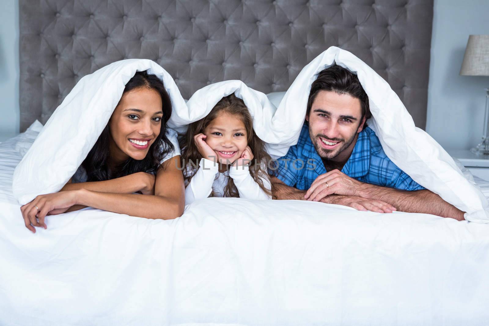 Happy family under the blanket posing for camera