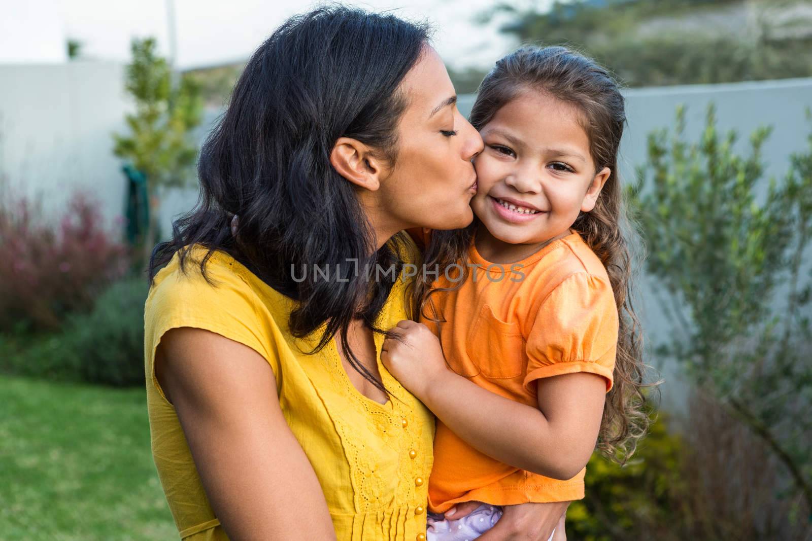 Lovely mother kissing her daughters cheek by Wavebreakmedia