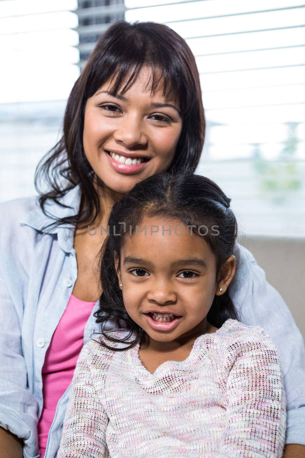 Portrait of happy mother with her daughter in living room