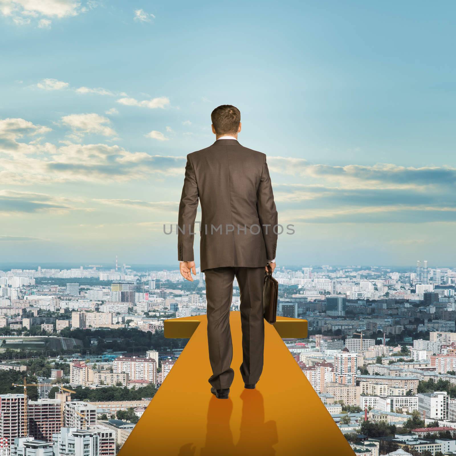 Businessman on gold arrow above city, rear view