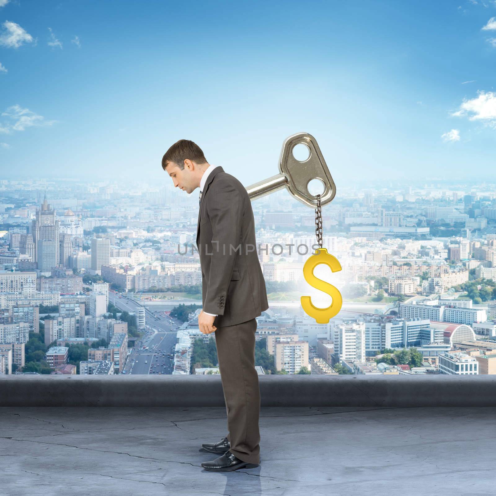 Businessman looking down with key in back with city background