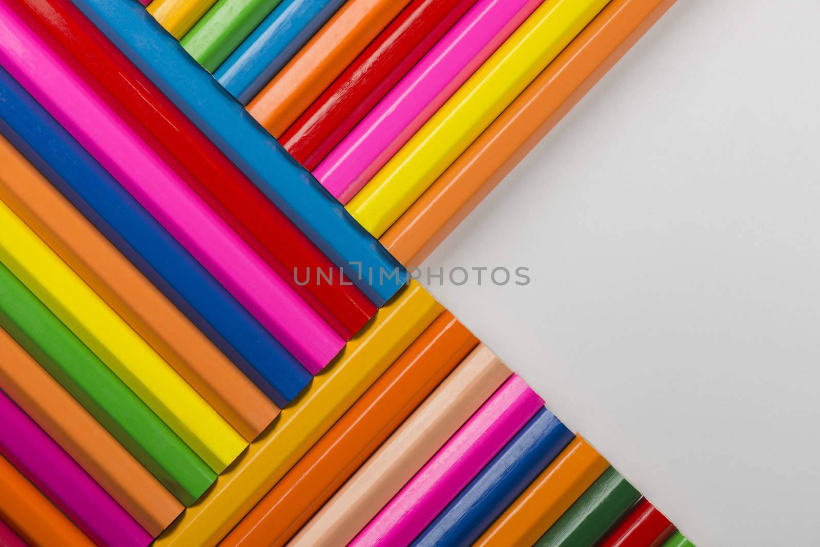 Abstract composition of a set wooden colour pencils against a white background
