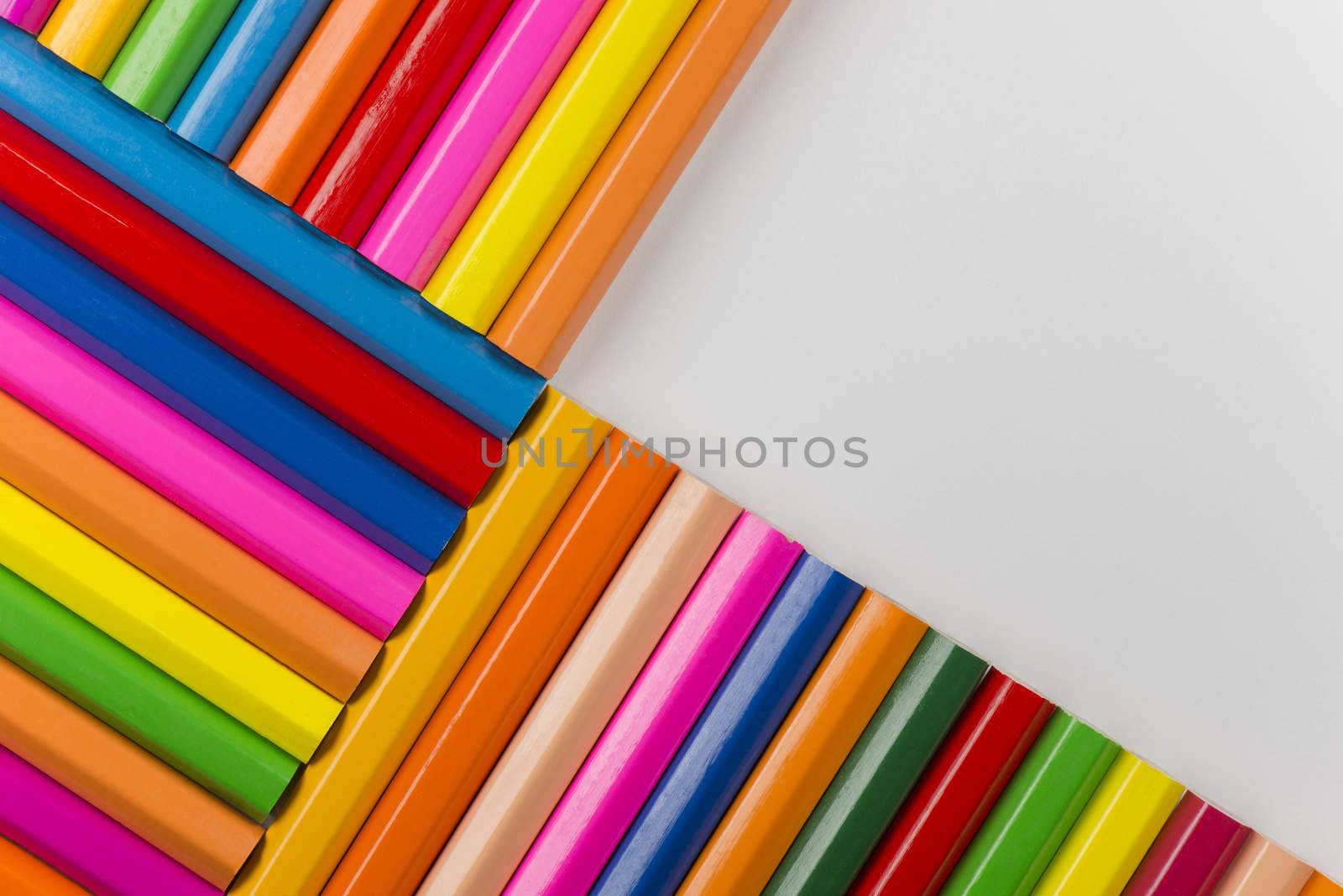 Abstract composition of a set wooden colour pencils against a white background
