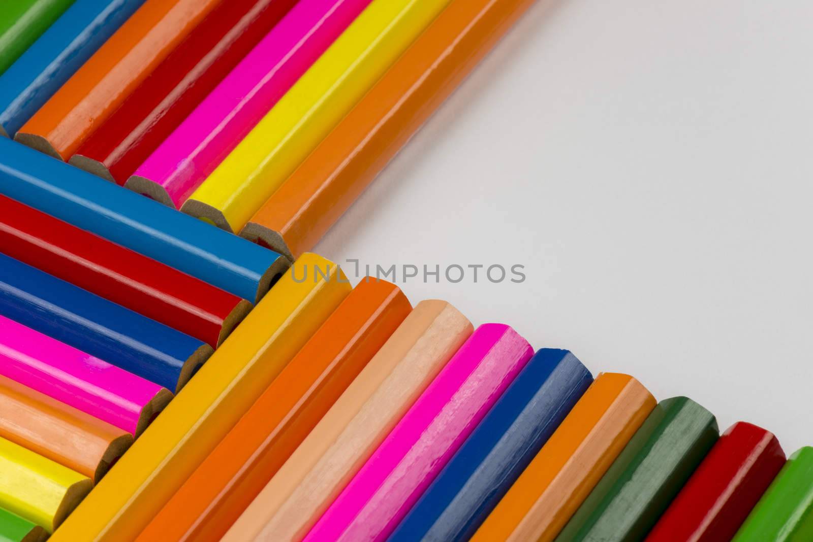 Abstract composition of a set wooden colour pencils against a white background
