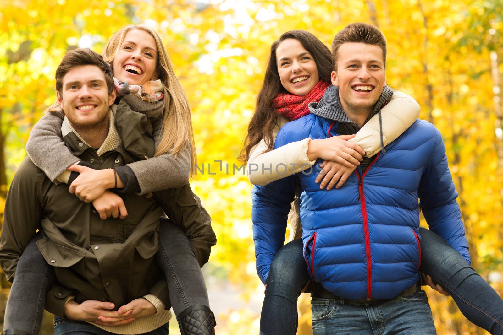 smiling friends having fun in autumn park by dolgachov