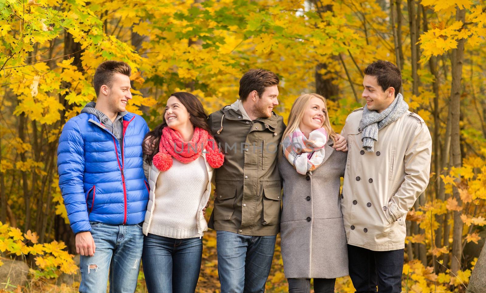 group of smiling men and women in autumn park by dolgachov