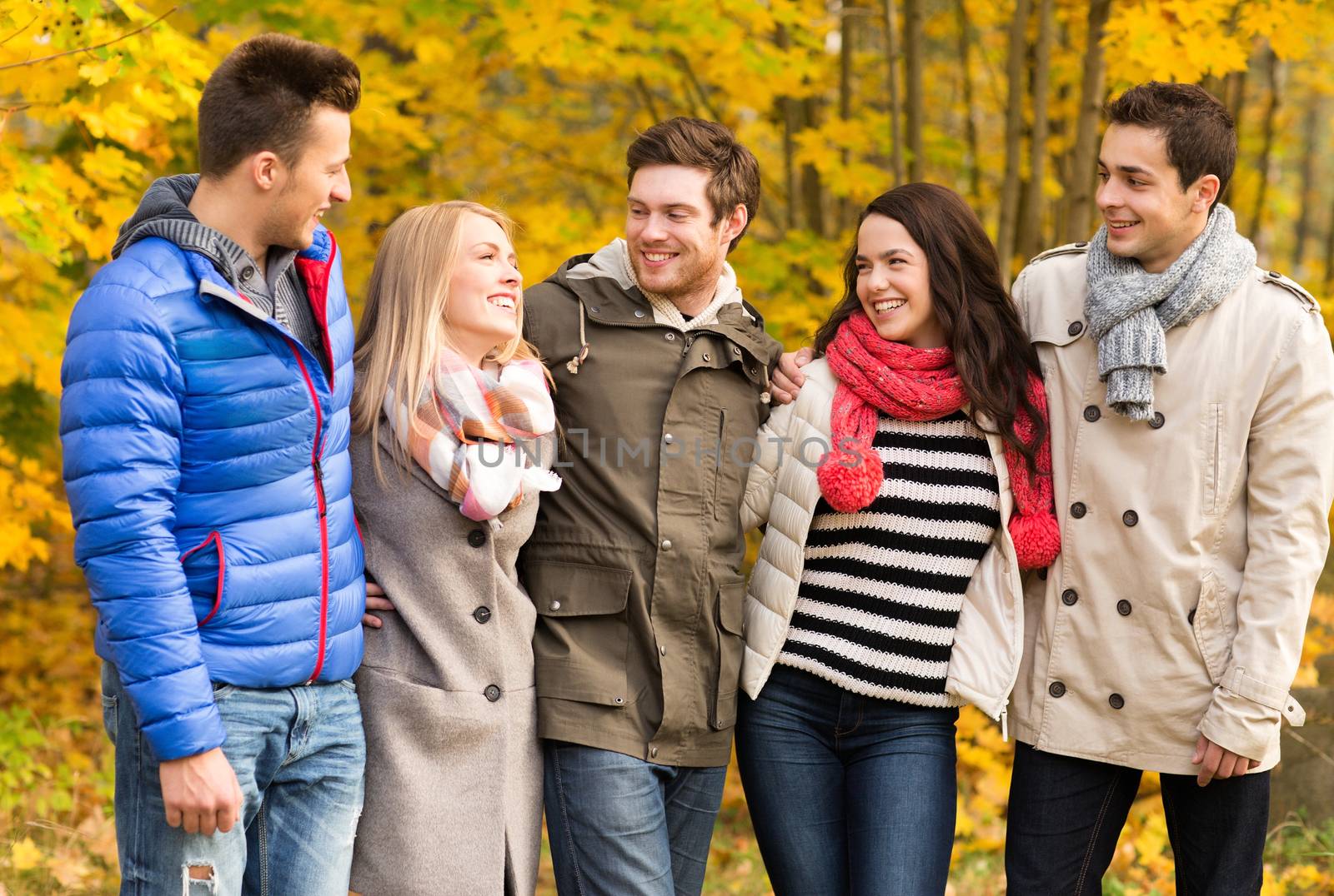 love, relationship, season, friendship and people concept - group of smiling men and women hugging in autumn park