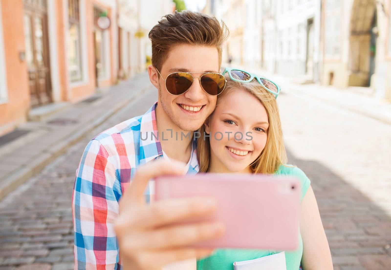 smiling couple with smartphone in city by dolgachov