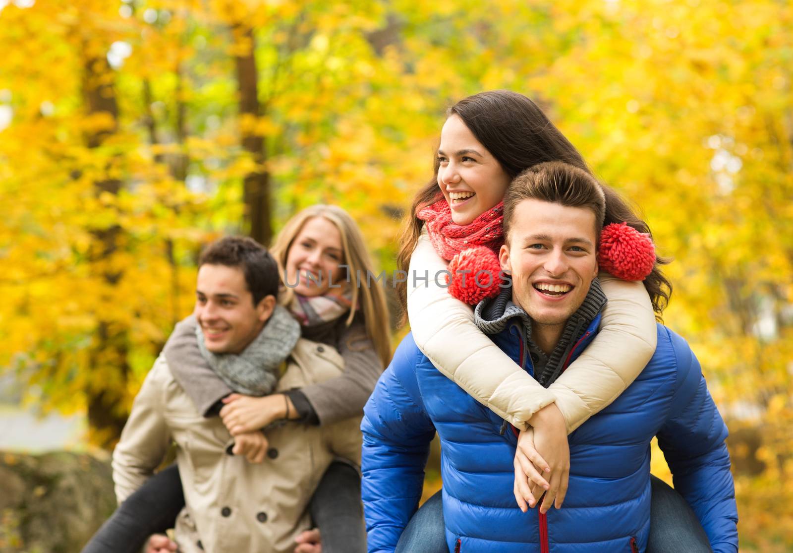 love, friendship, family and people concept - smiling friends having fun in autumn park