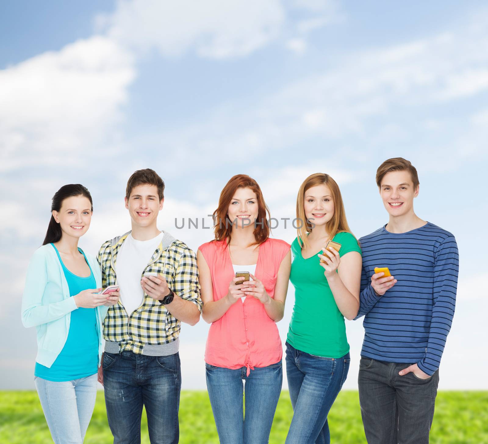 smiling students with smartphones by dolgachov