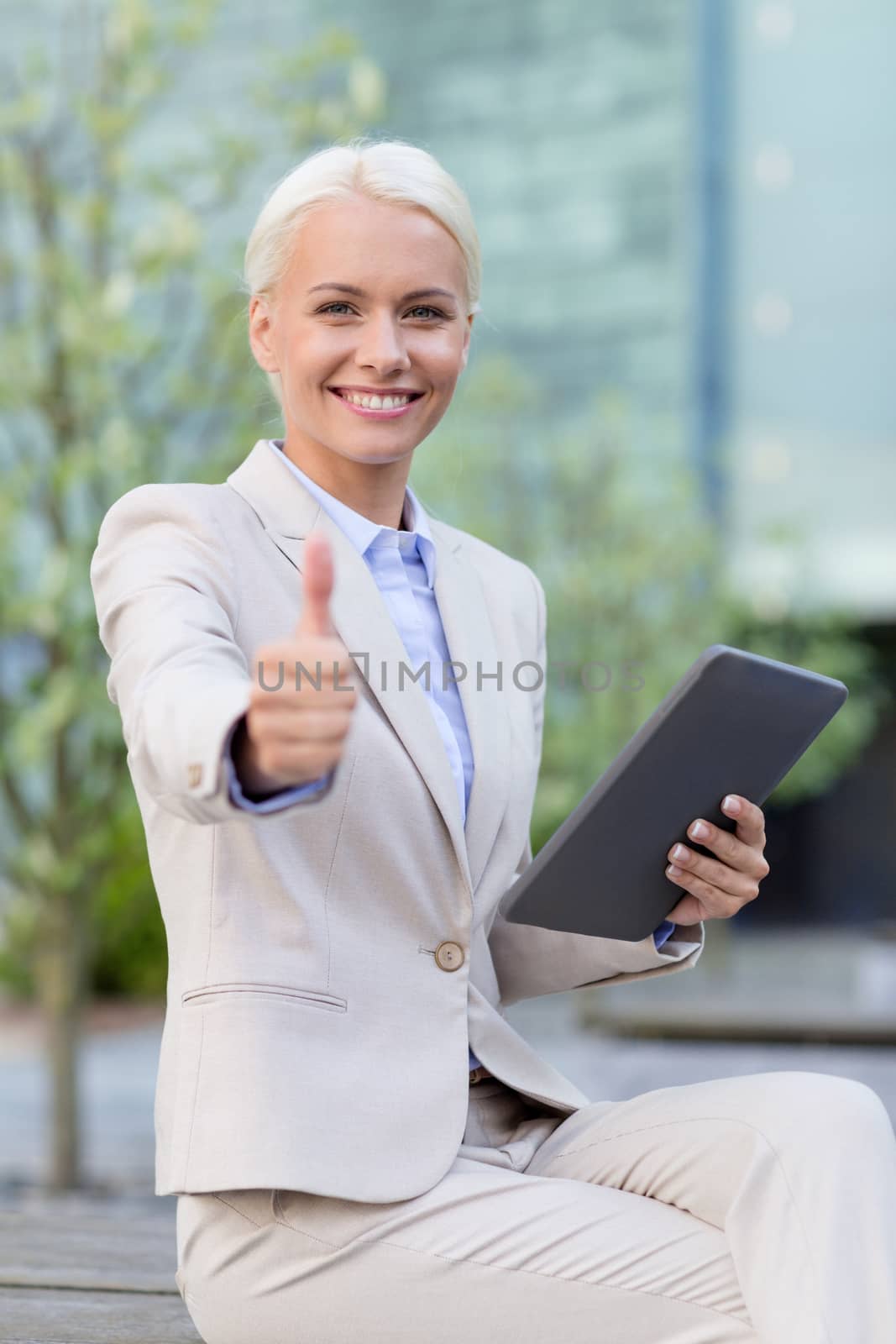 business, education, technology, gesture and people concept - smiling businesswoman working with tablet pc computer showing thumbs up on city street