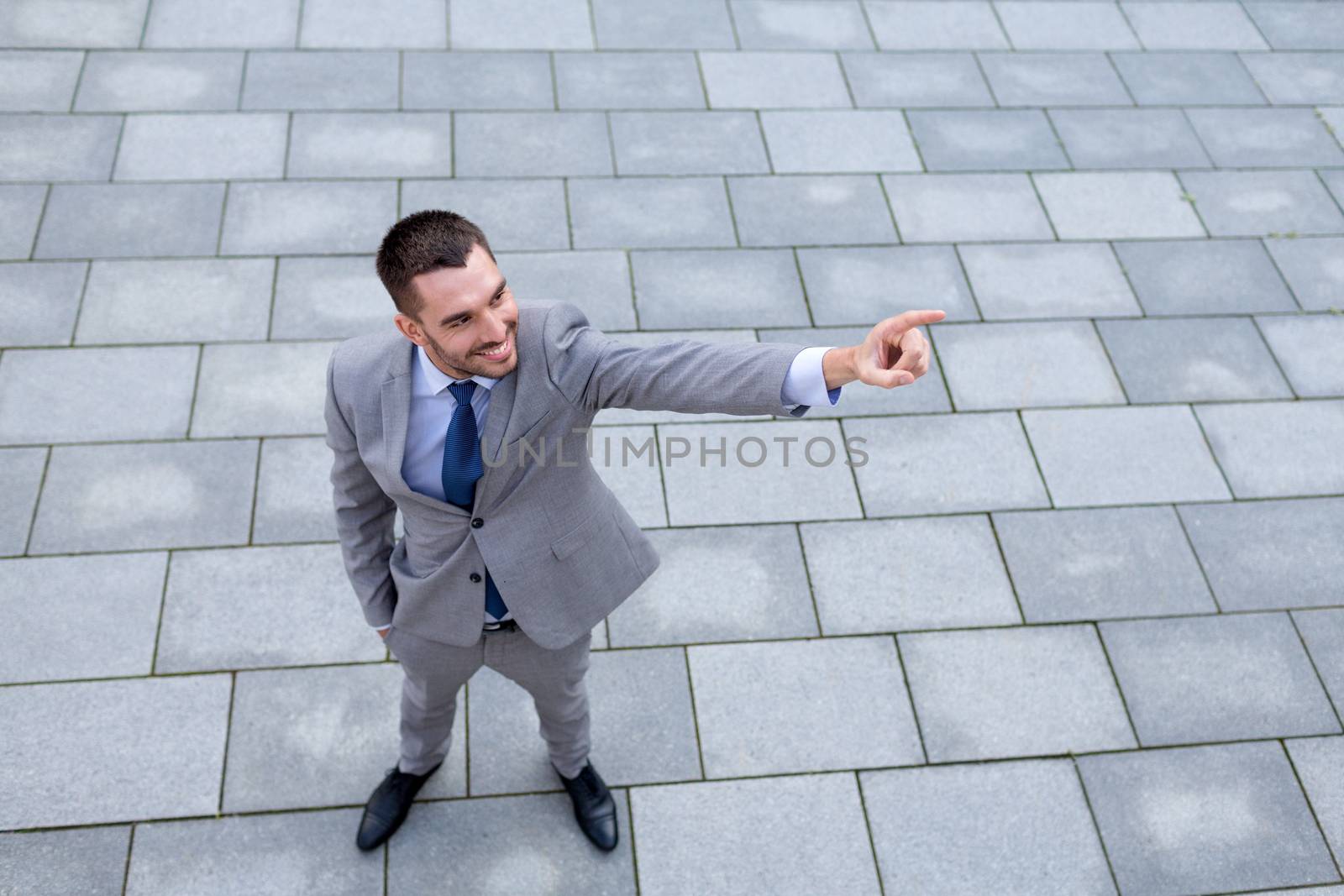 business, development and people and concept - young smiling businessman pointing finger outdoors from top