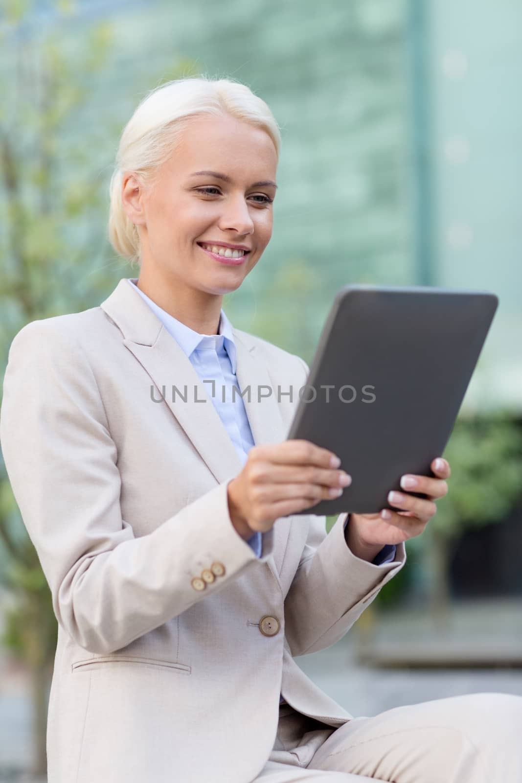 smiling businesswoman with tablet pc outdoors by dolgachov
