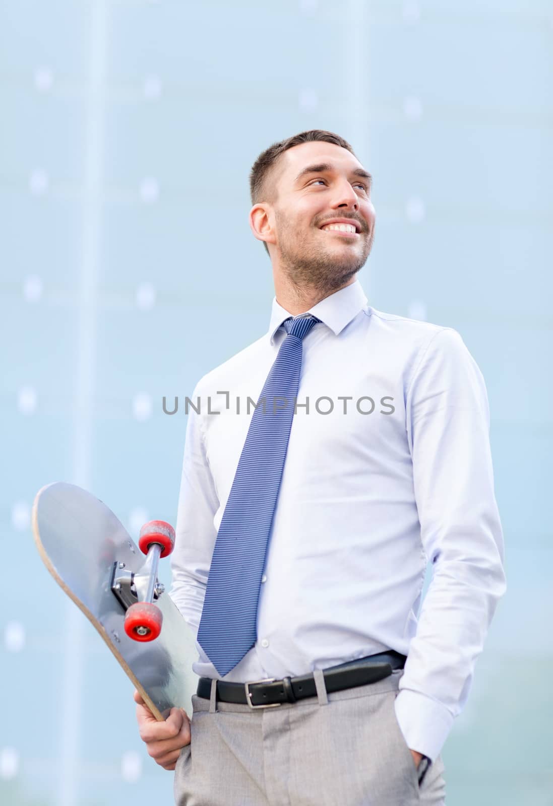 young smiling businessman with skateboard outdoors by dolgachov
