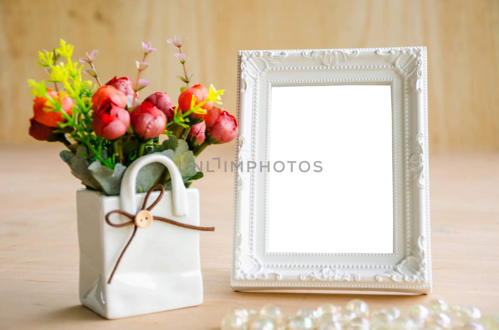 Blank vintage photo fame and flower on wooden background. Save with clipping path.