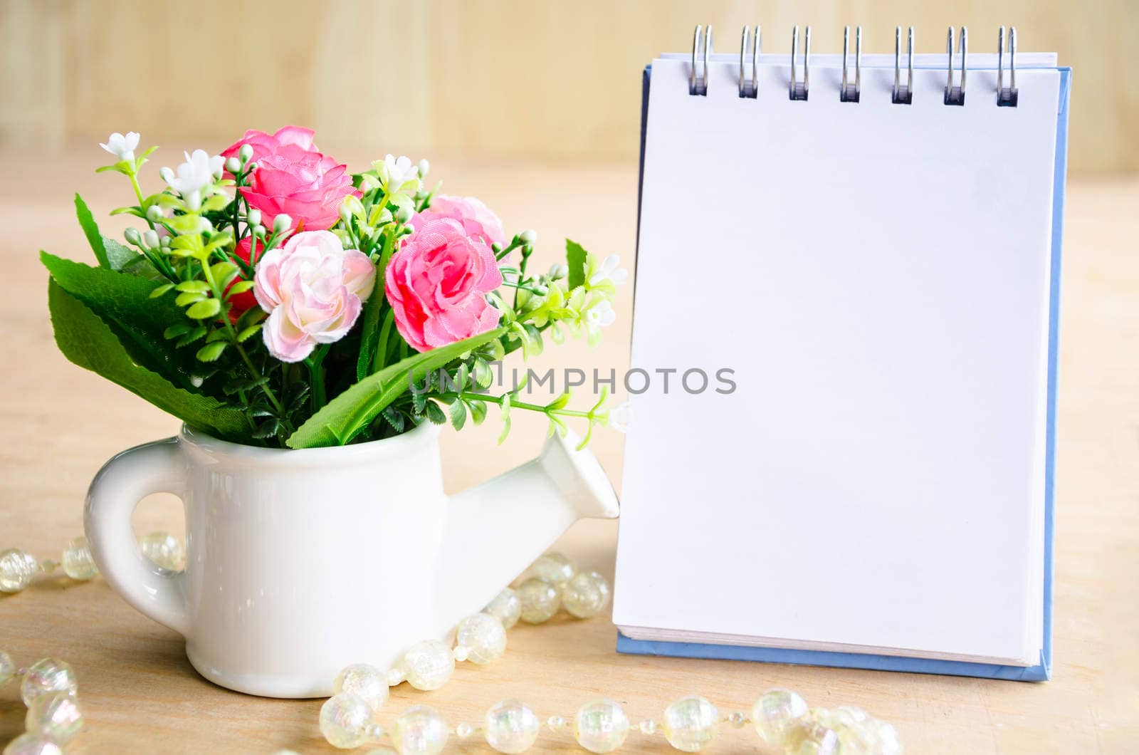 Open blank diary and flower on wooden background.