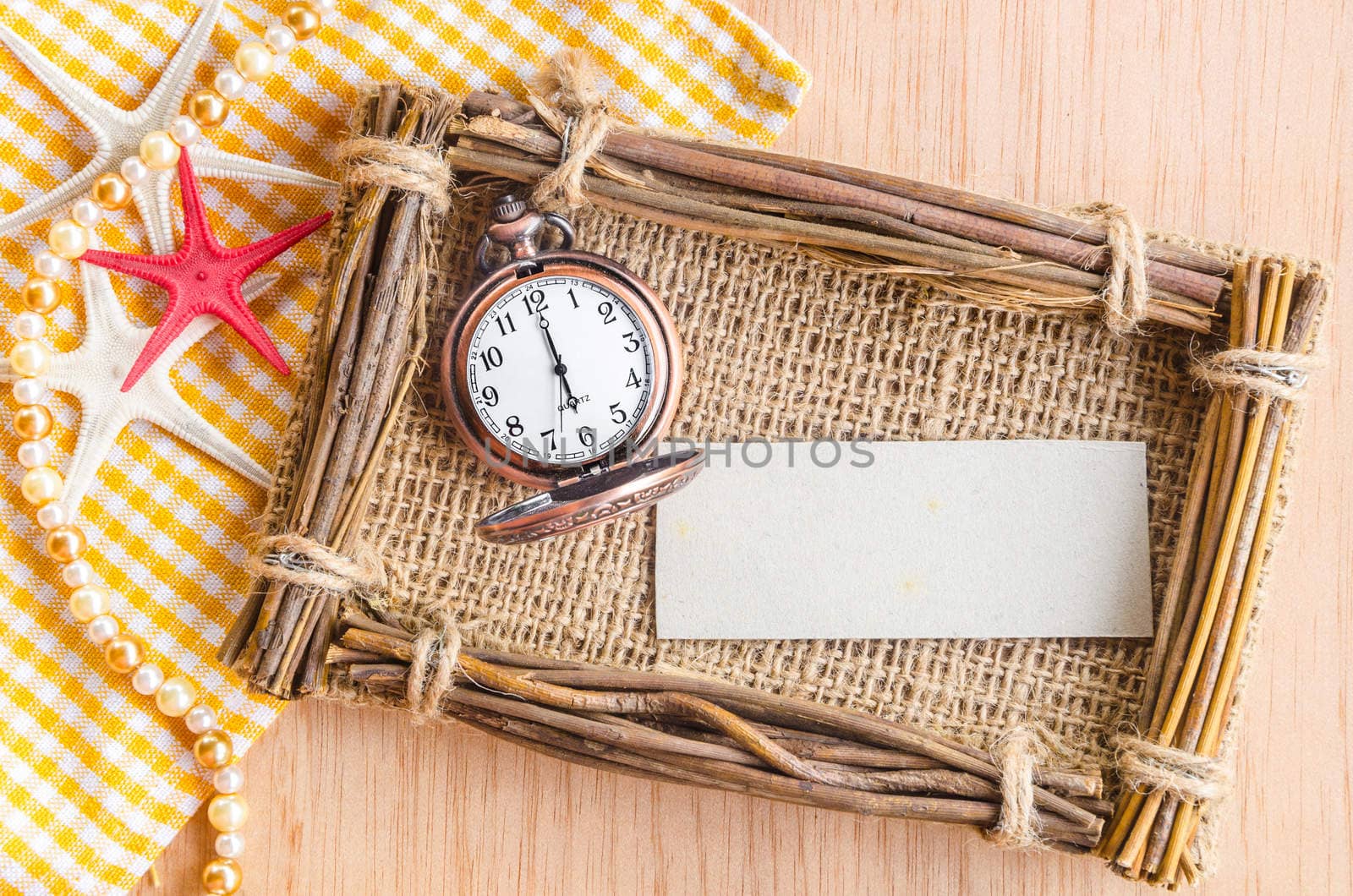Blank tag paper and vintage pocket watch at 6 AM on wooden background.
