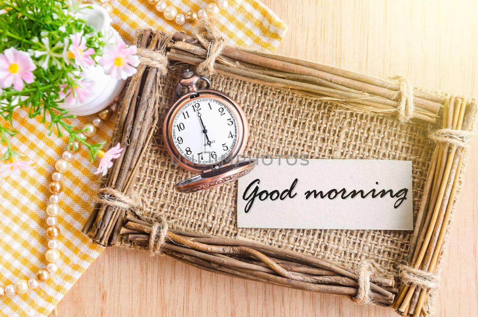 Good morning text in sack photo frame with flower on wooden background.