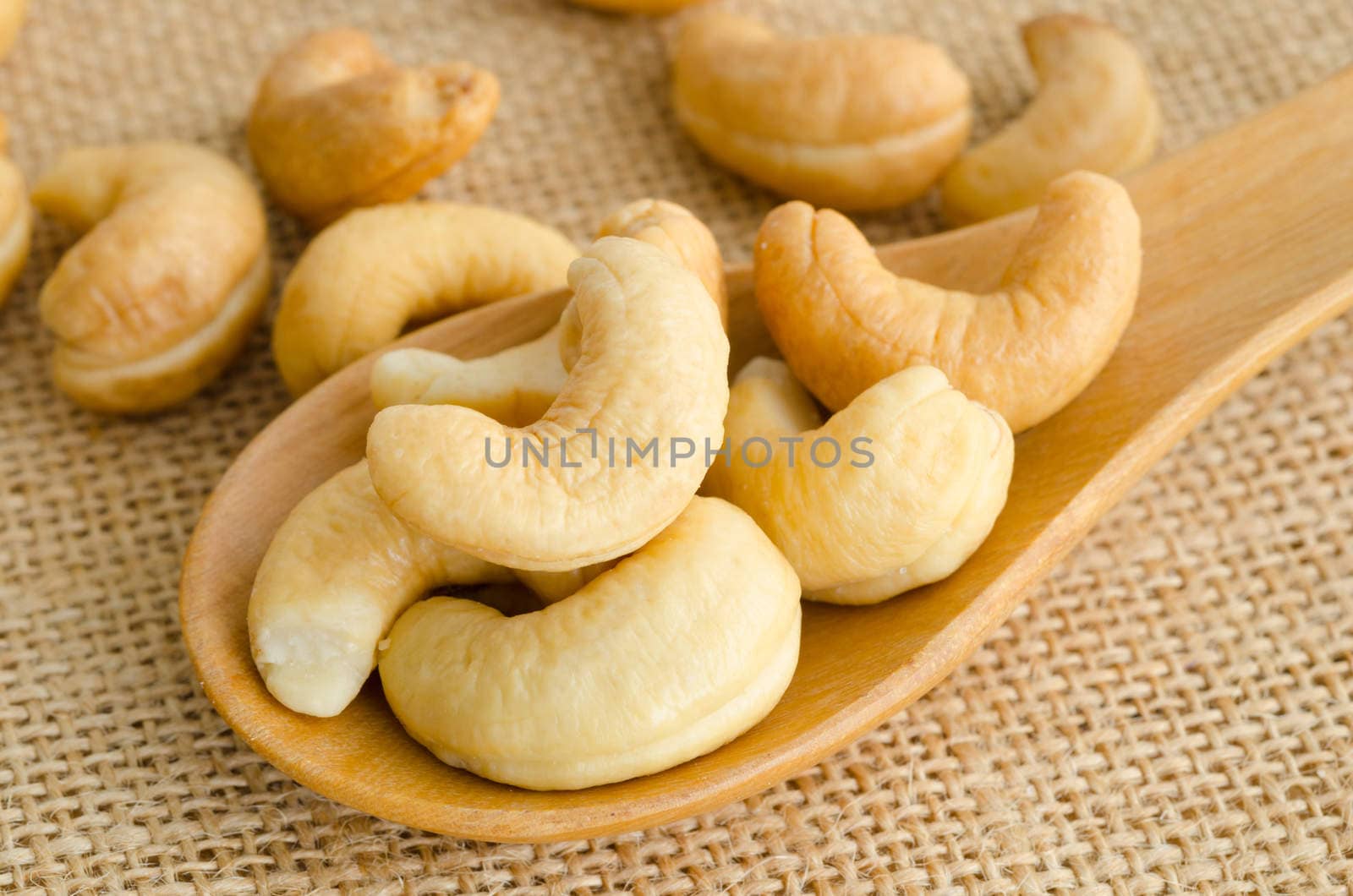 Cashews close-up in wooden spoon on sackcloth