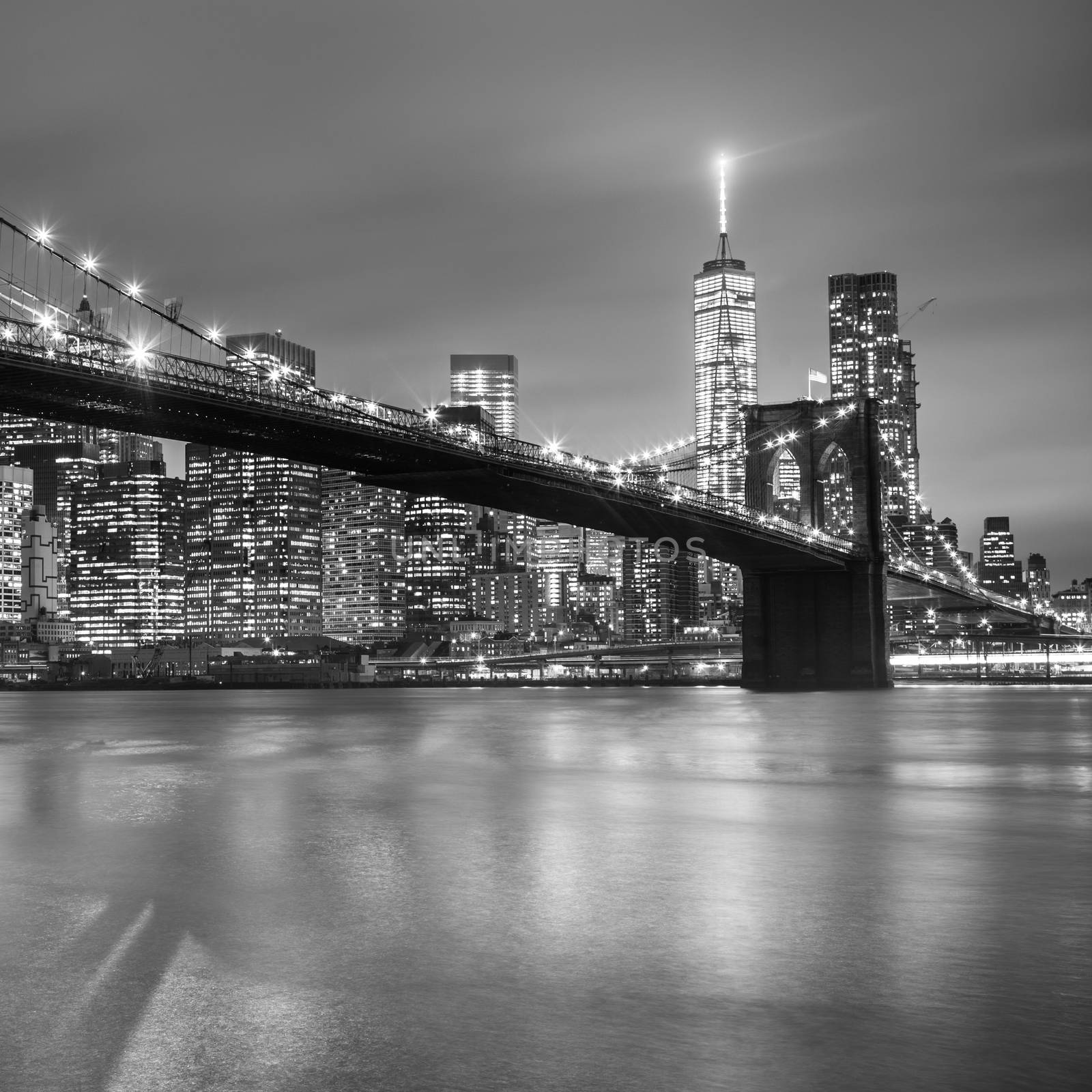 Brooklyn bridge and New York City Manhattan downtown skyline at dusk with skyscrapers illuminated over East River panorama. Copy space. Black and white image. Square image.