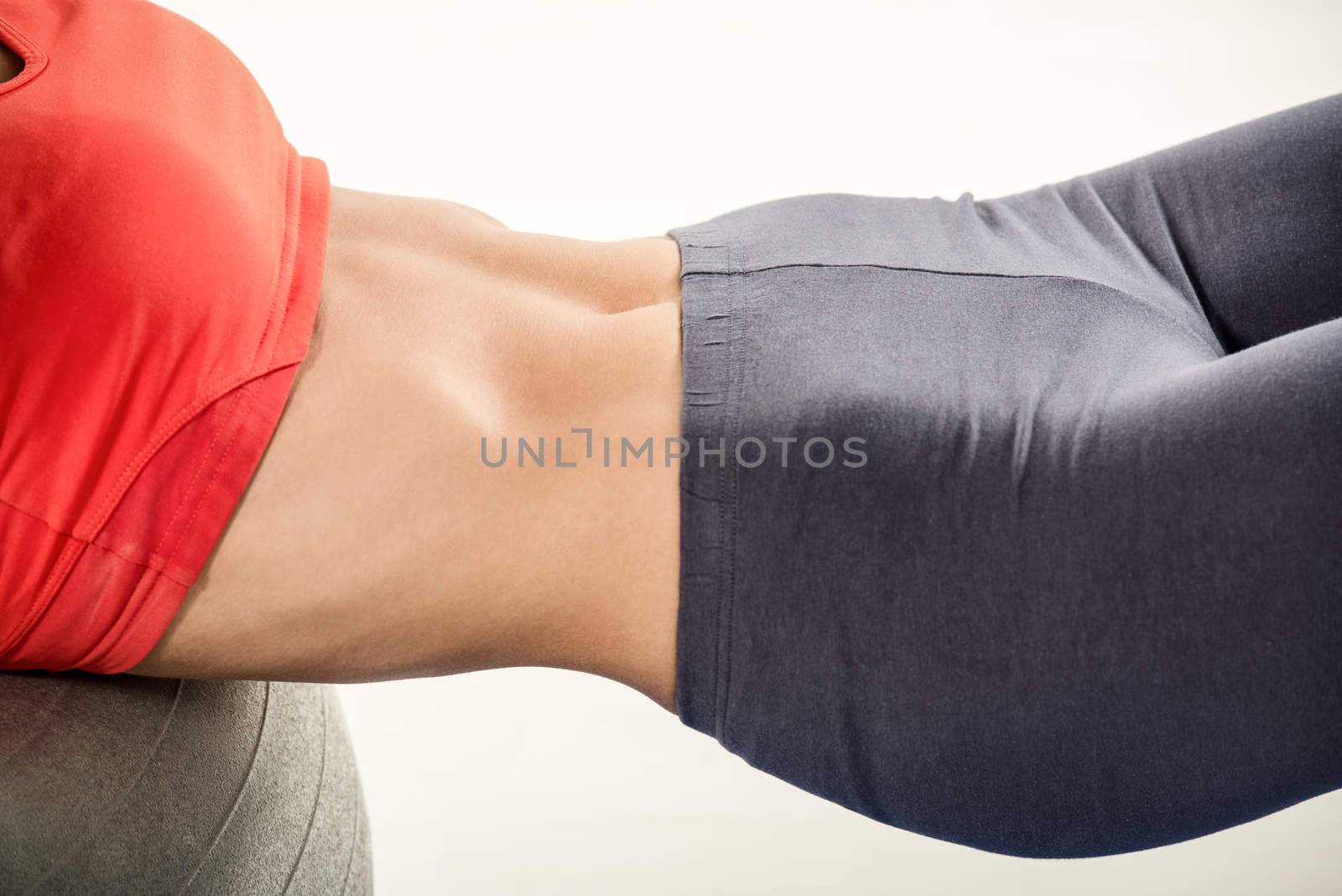 Close-up of the women abs while doing sit-ups on a fitness ball. 