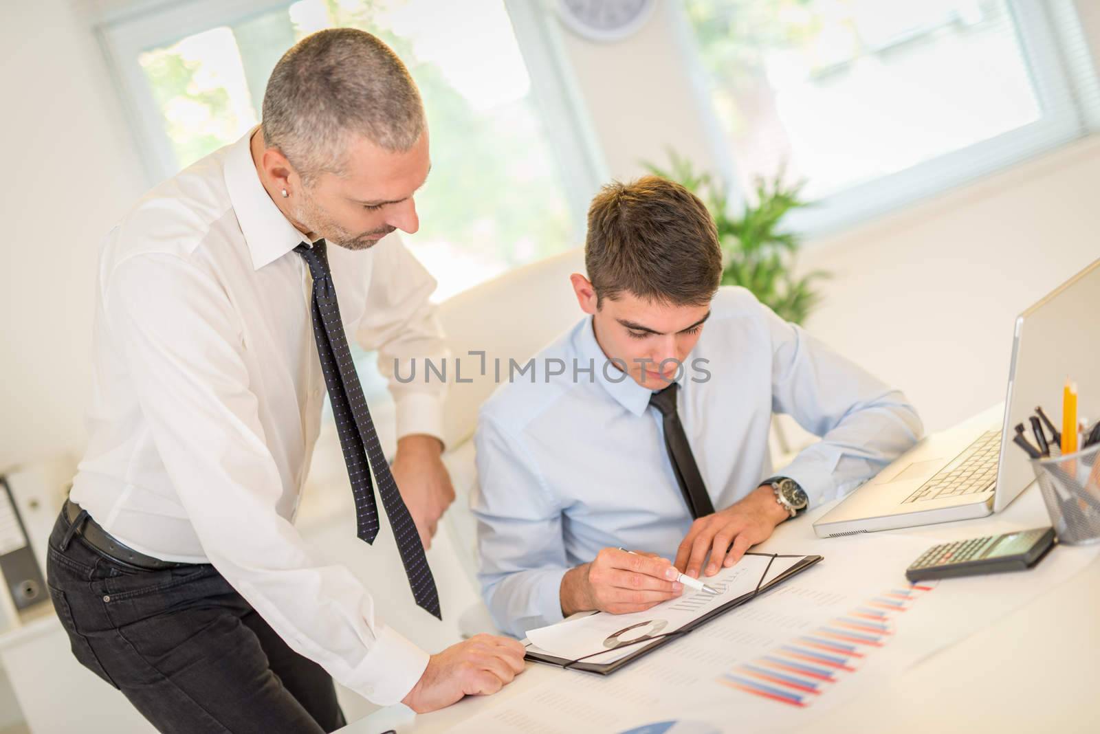 Businessman discussing and looking at document with male colleague in the office.