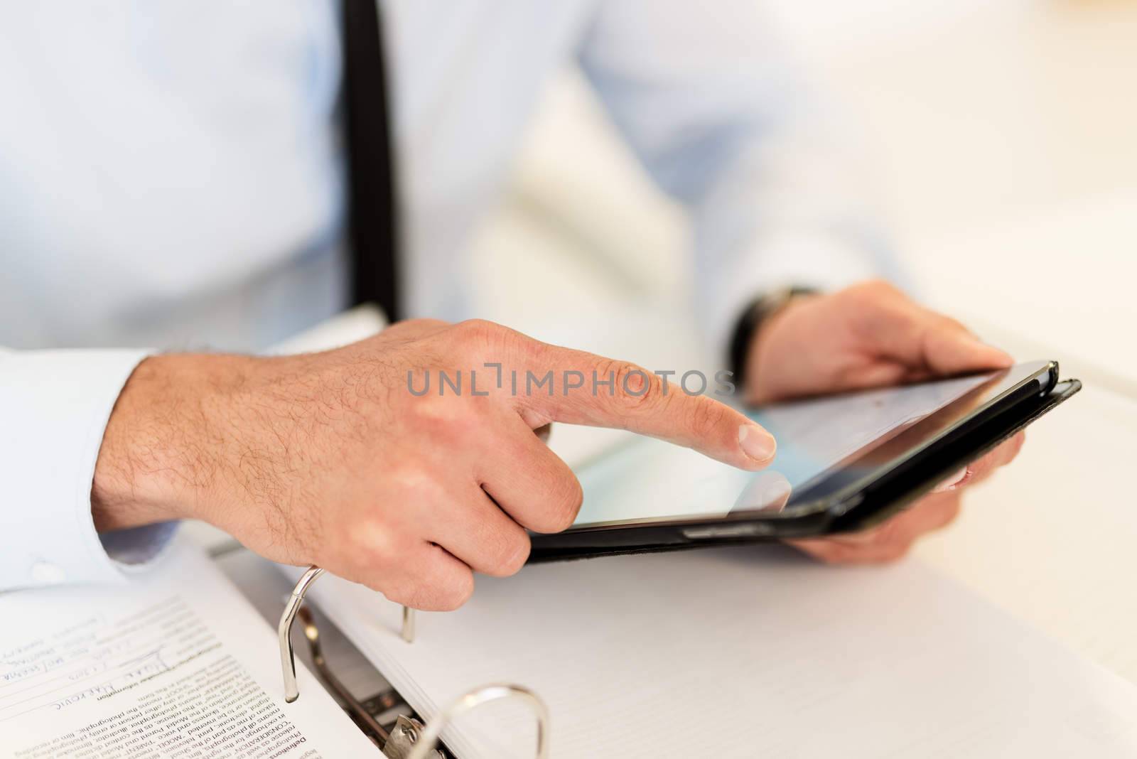 Close-up of a businessman hands touching his digital tablet.