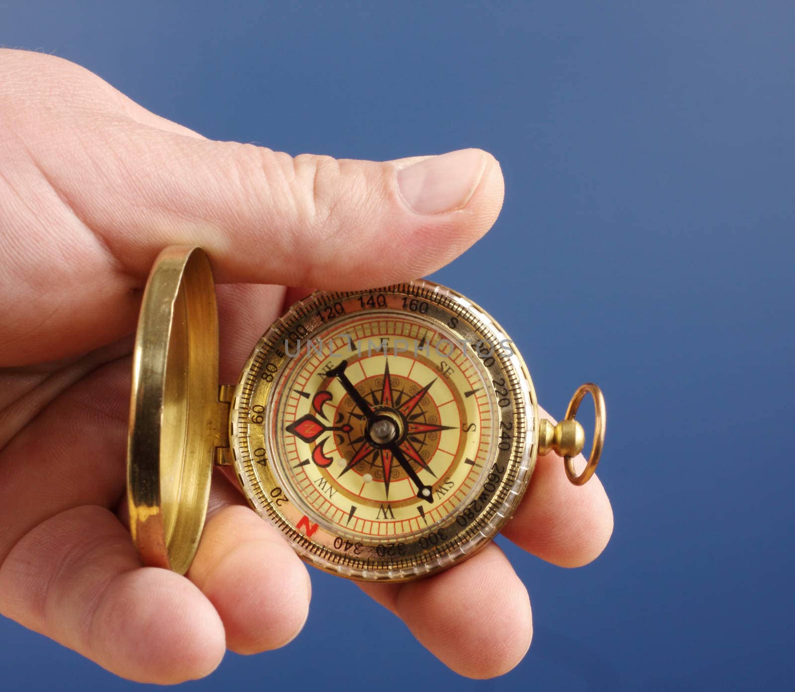 male hand holding compass over blue
