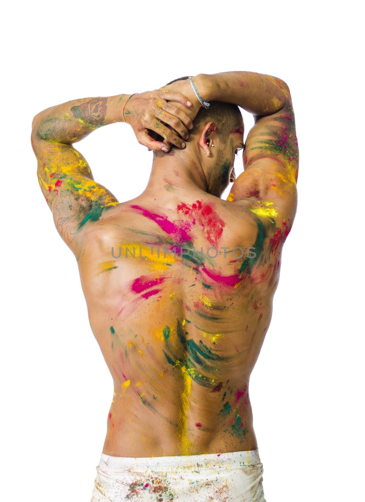 Handsome young man seen from the back with skin all painted with Holi colors, isolated on white background
