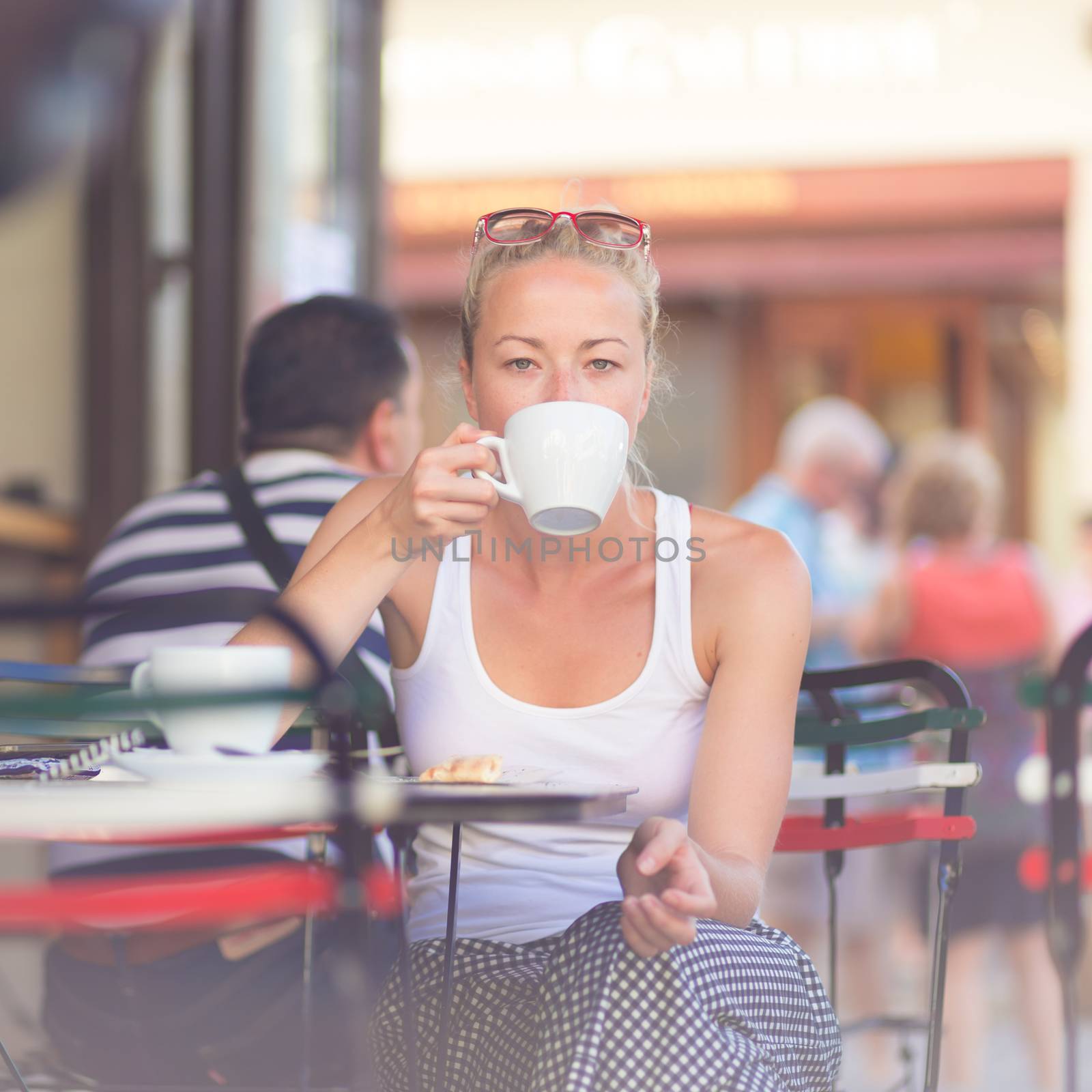 Woman drinking coffee outdoor on street. by kasto