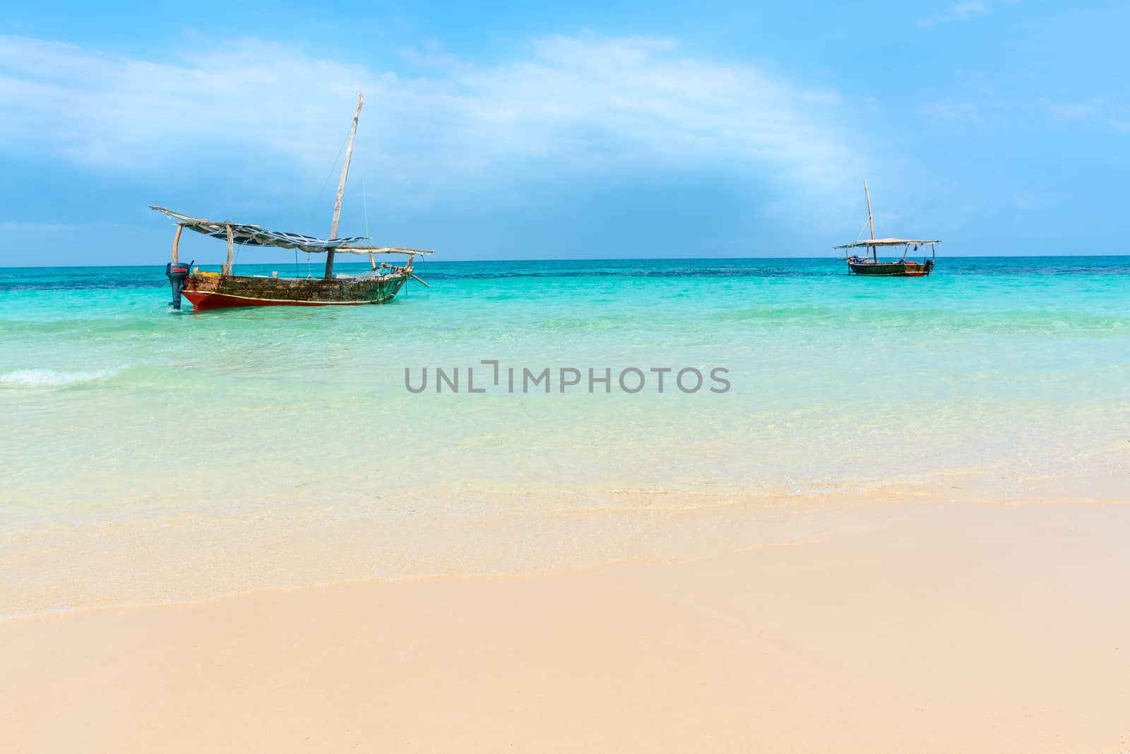 Anchored wooden dhow boats on the amazing turquoise water in the Indian ocean  Zanzibar, Tanzania.