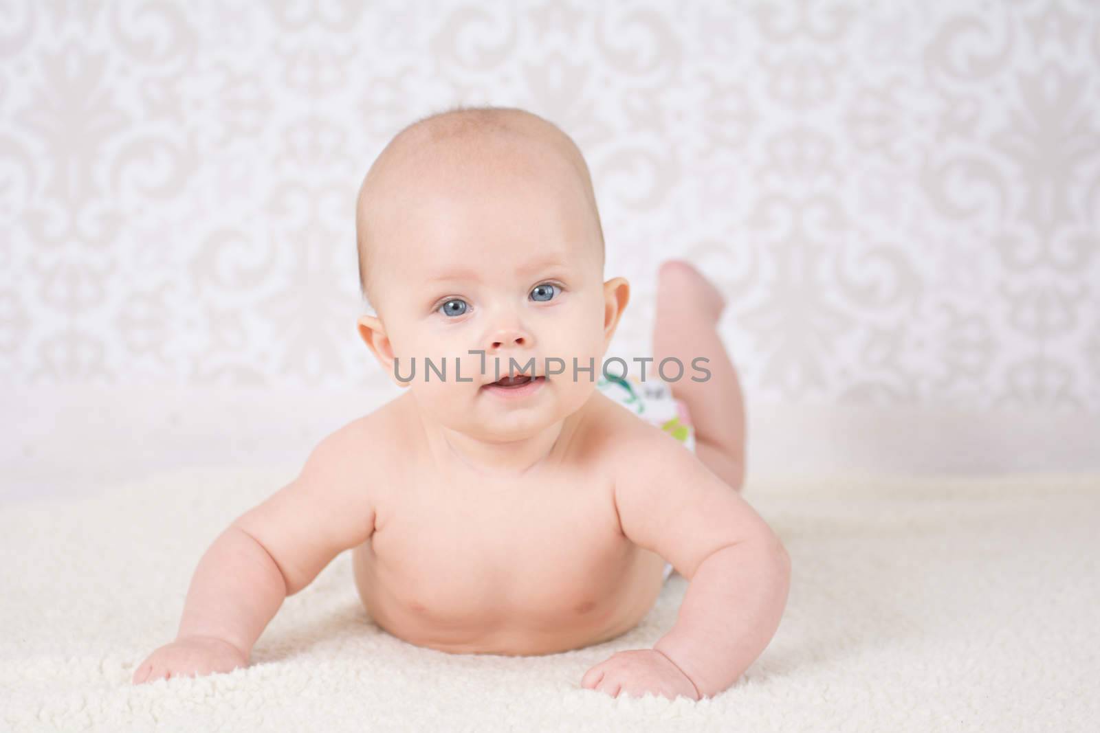 Baby in a reusable nappy, lying on a belly on a light background
