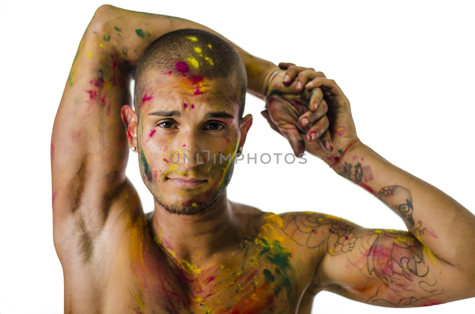 Head and shoulders shot of attractive young man shirtless, skin painted all over with bright Holi colors, looking at camera, isolated on white background