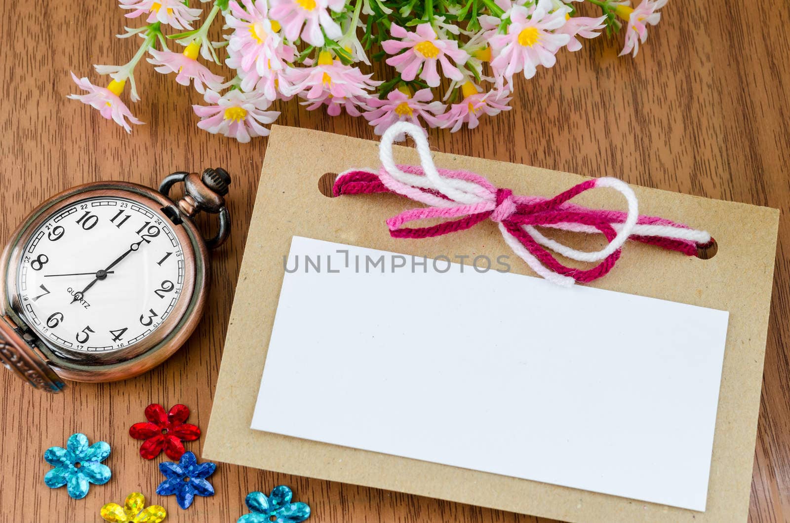 Blank tag and vintage pocket watch with flower on wooden background.