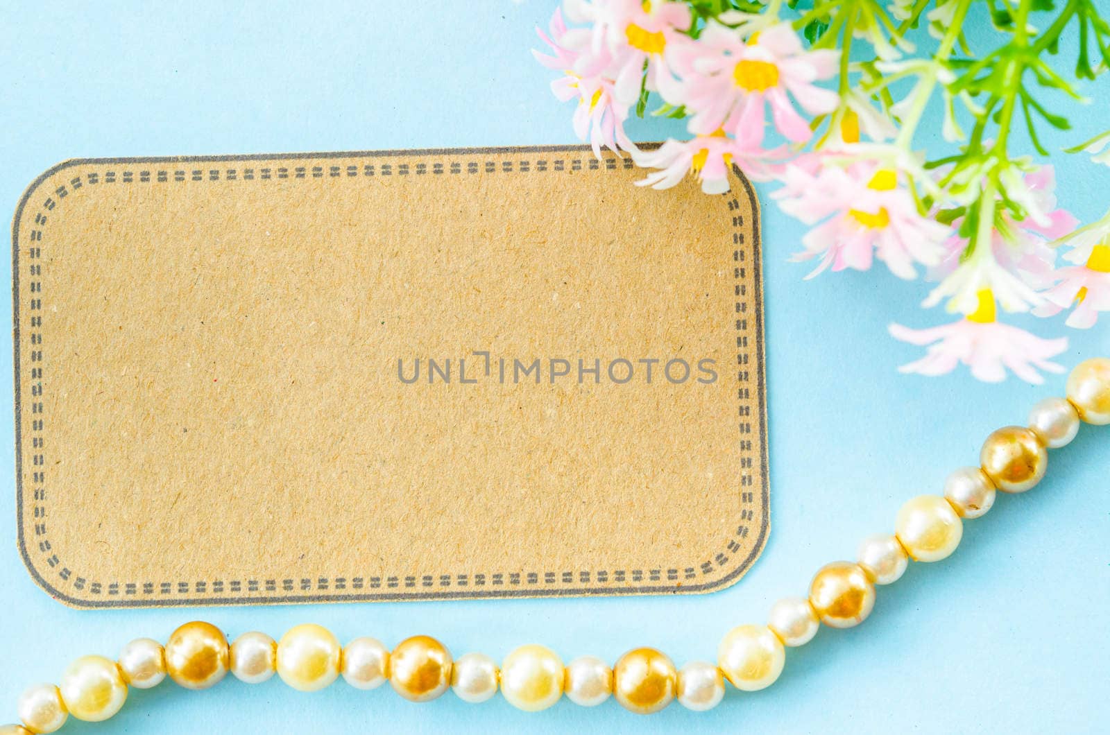 Blank brown paper tag and pink flower on blue background for your text.