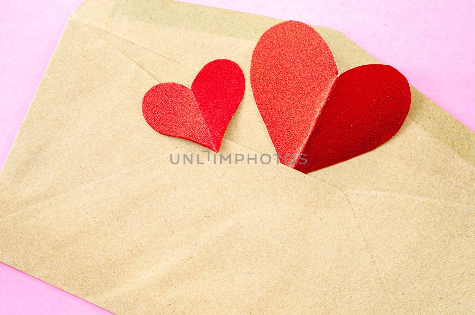 red heart paper in brown envelopes on pink background.