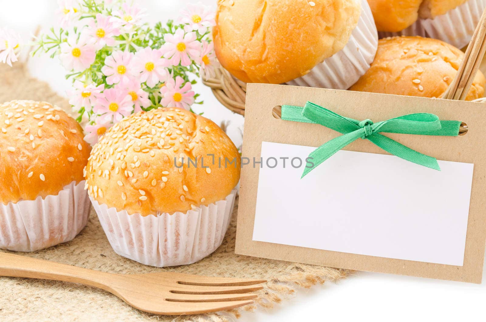 Bread bun and blank paper tag with flower on white background.