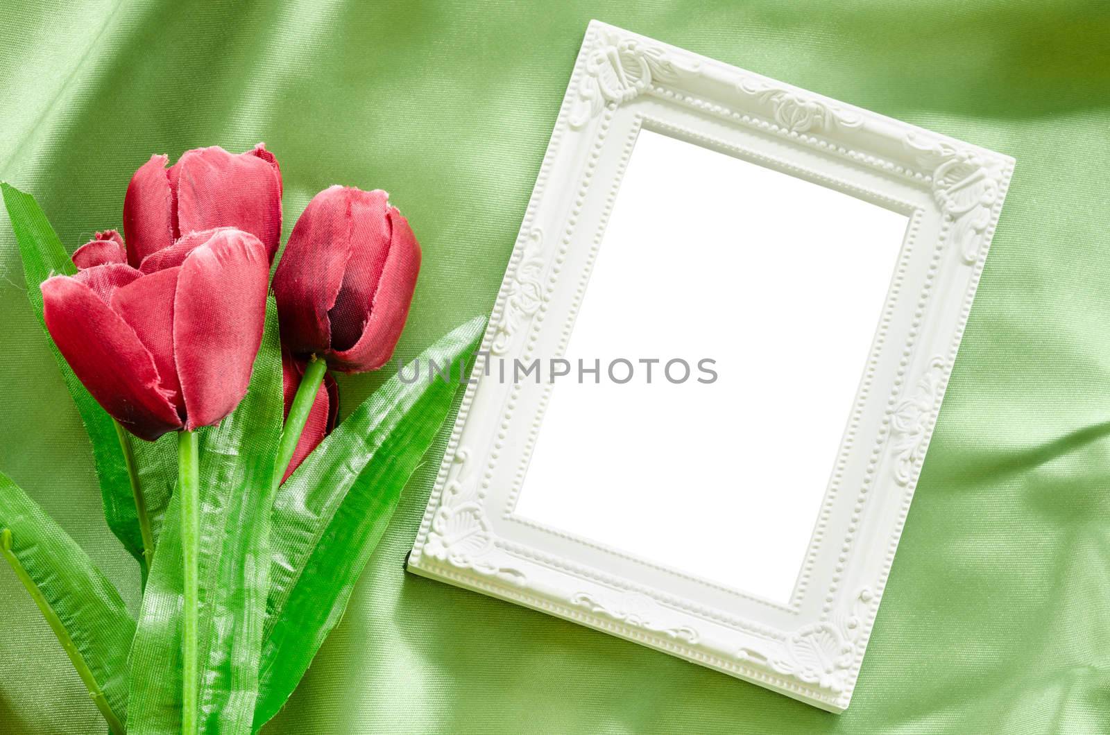 Blank Picture frames and red tulips flowers on green green silk fabric background. save clipping path.