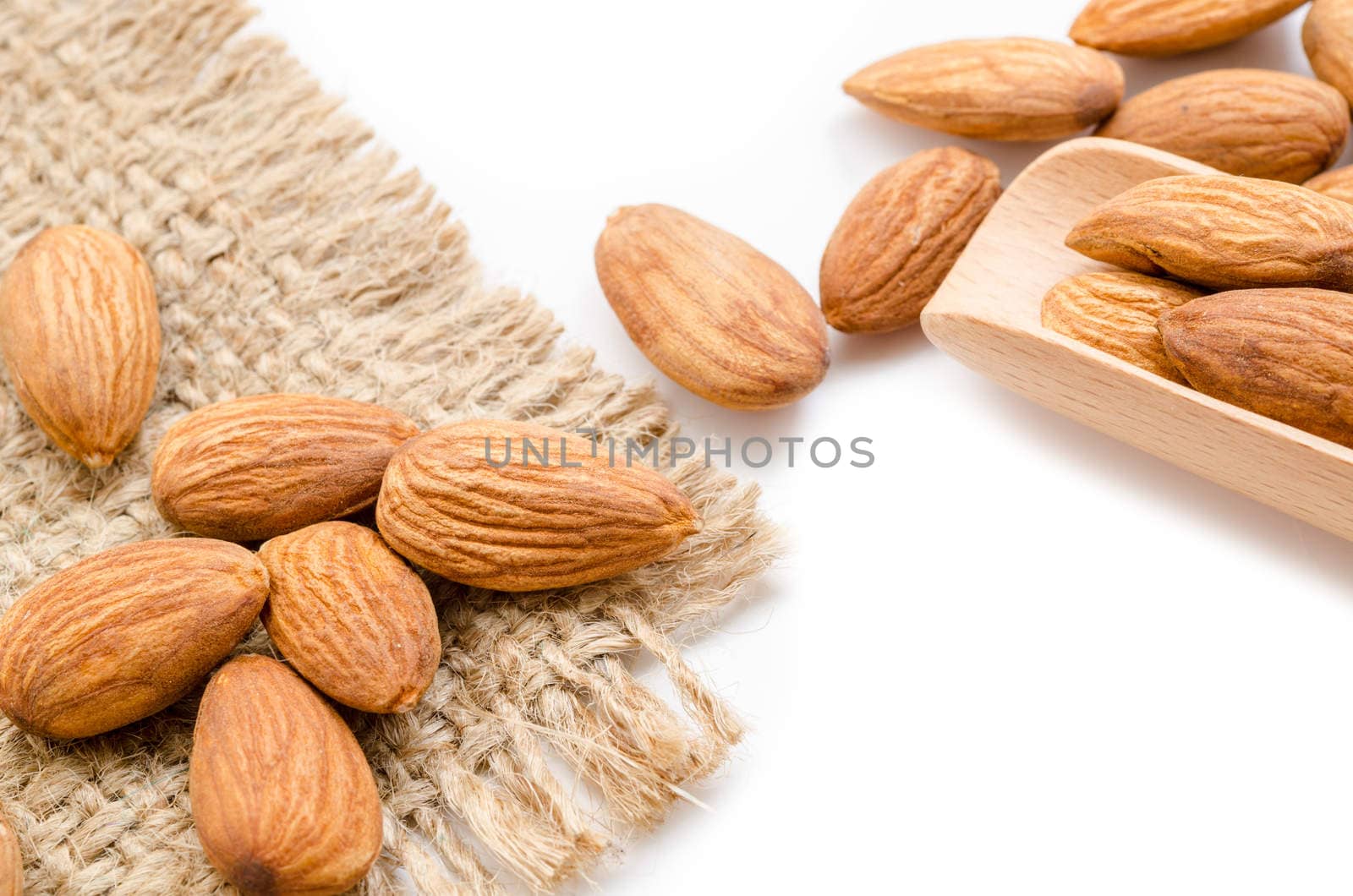 Close up raw almonds in wooden spoon on white background.