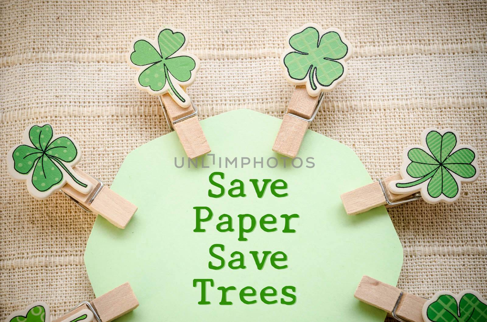 Save paper save trees on green paper and leaf wooden clamps on fabric background. Save world save life concept.