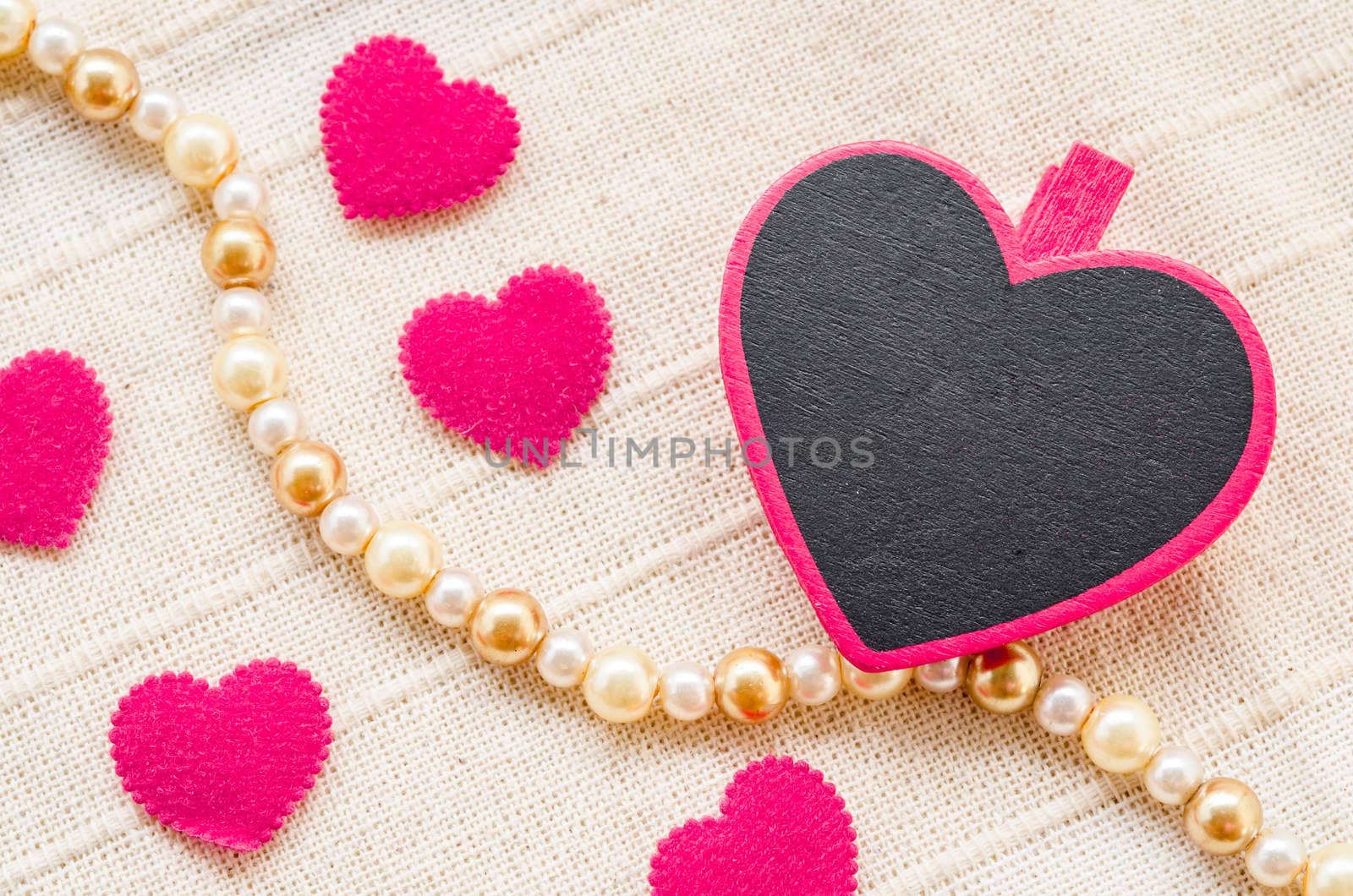 Blank pink heart wooden clamps and on fabric background.