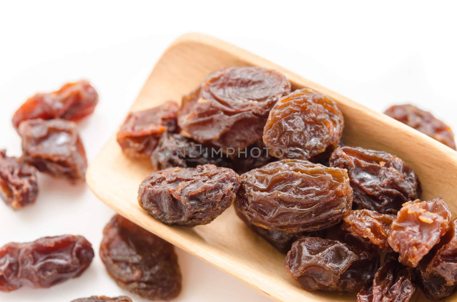 Raisins in a wooden spoon on white background. Close-up.