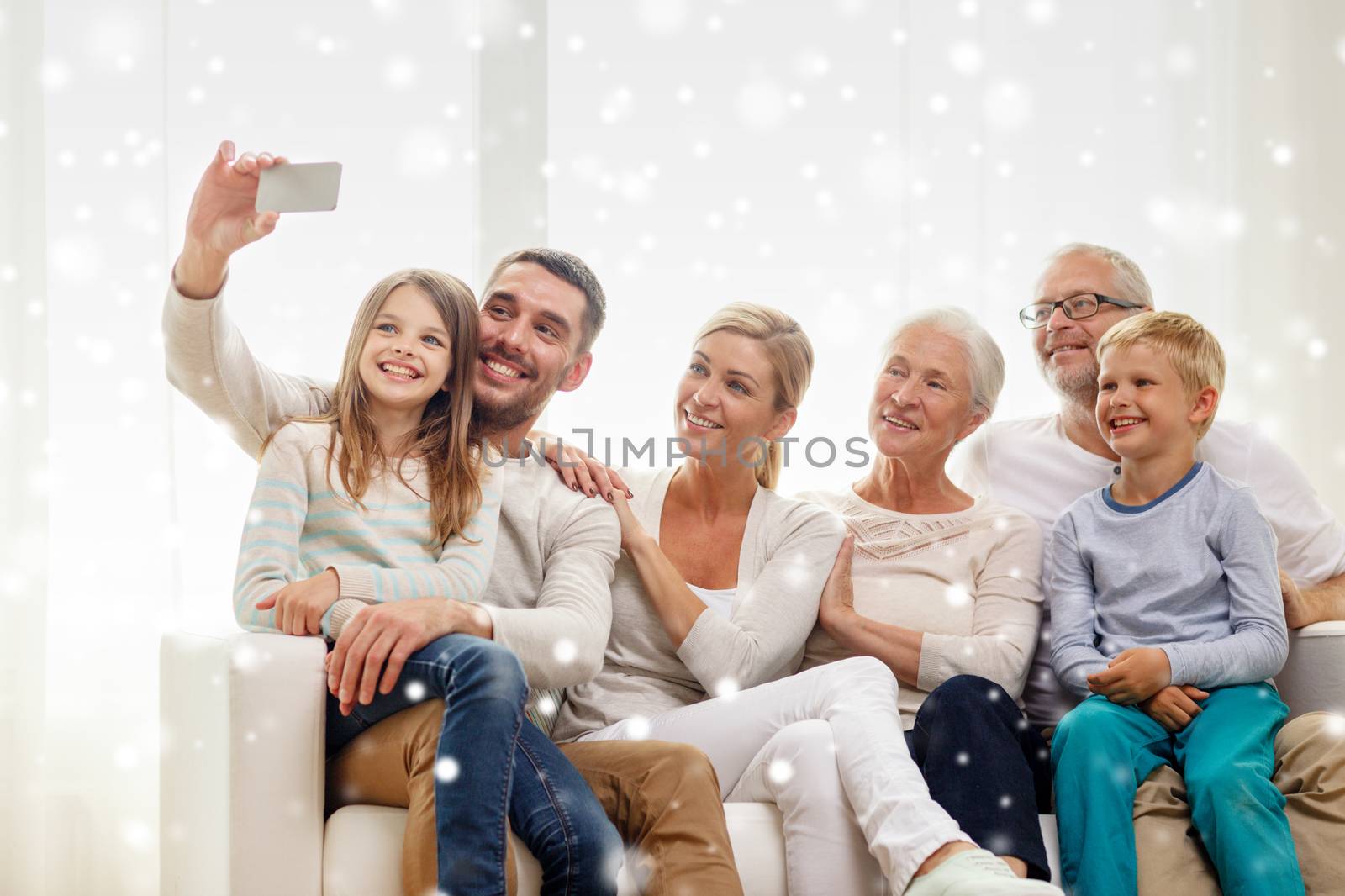 family, technology, generation and people concept - happy family sitting on couch and making selfie with smartphone at home