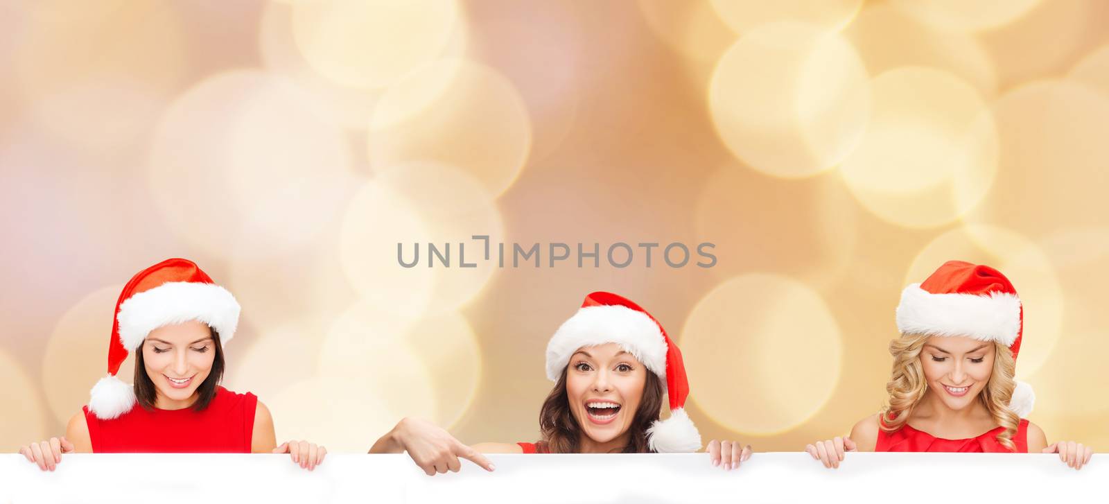 christmas, x-mas, people, advertisement and sale concept - happy women in santa helper hat with blank white board over beige lights background